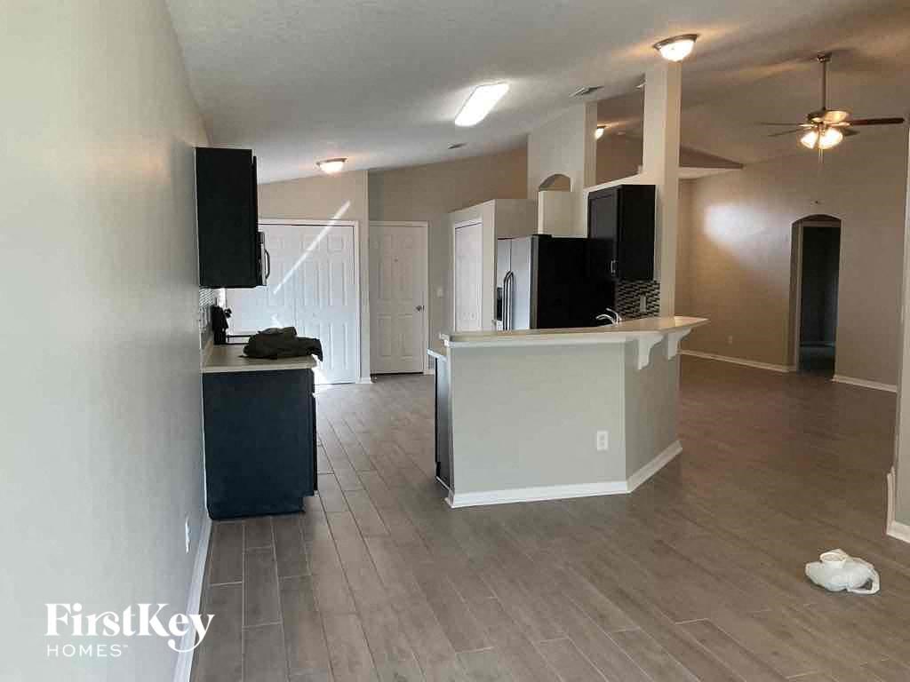 A spacious living room with a kitchenette and a ceiling fan.