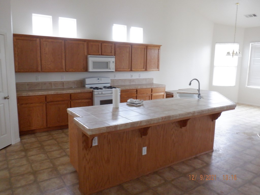 A kitchen with wooden cabinets and a tiled floor.