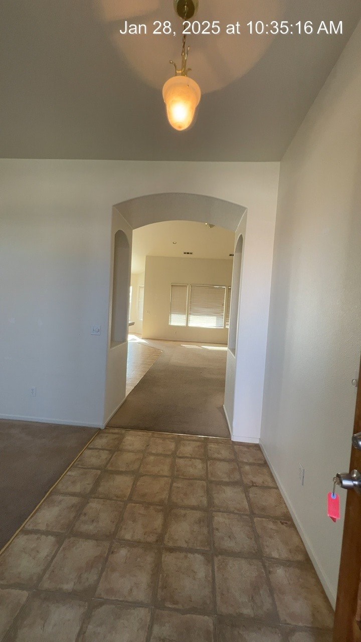 A hallway with a tiled floor and a light hanging from the ceiling.