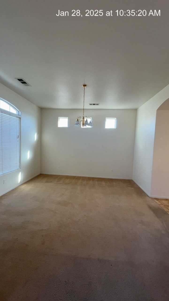 A room with a light fixture hanging from the ceiling and two windows.