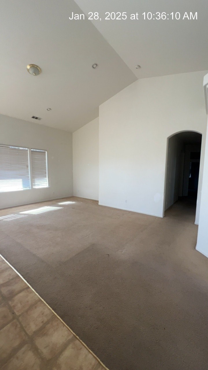 A room with a carpeted floor and a window with blinds.