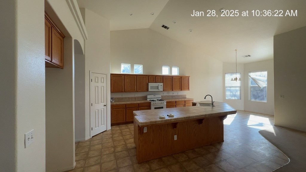 A kitchen with wooden cabinets and a countertop is shown in a house under construction.