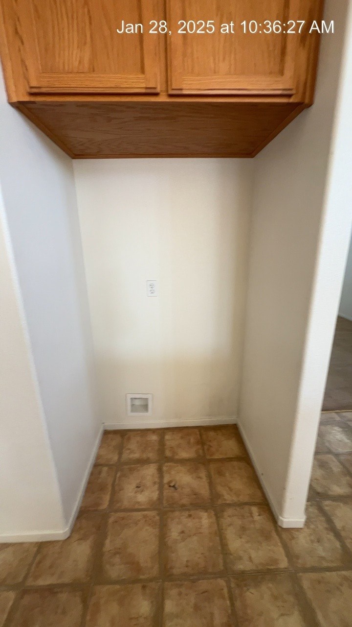 A small, empty room with wooden cabinets and tiled flooring.