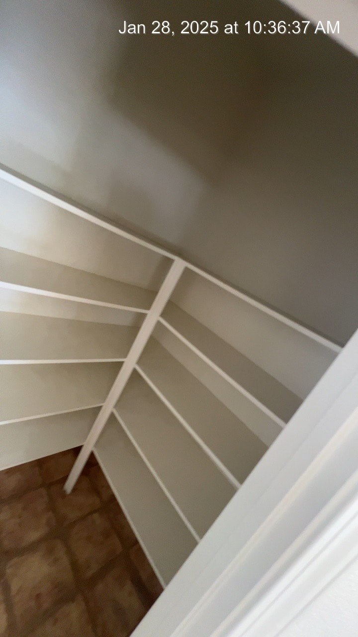 A spiral staircase with white railings and a brown floor.