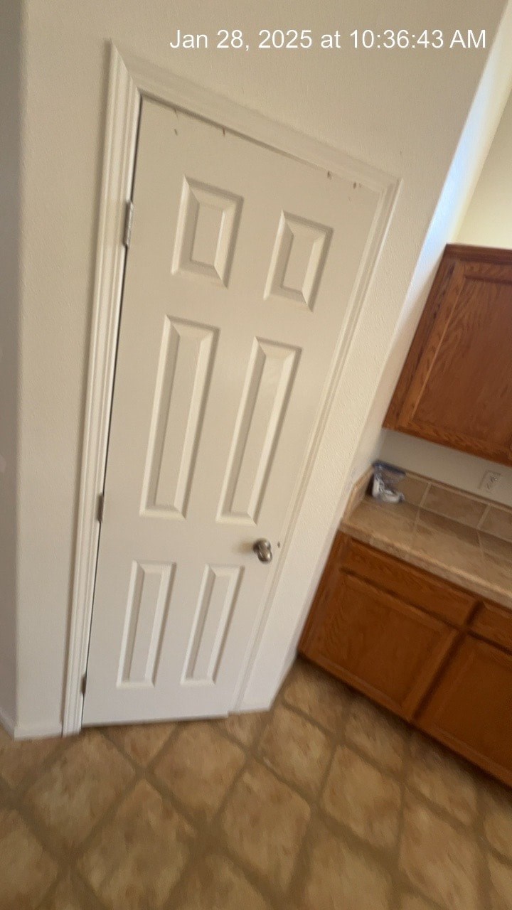 A white door is open in a room with brown tiled flooring.