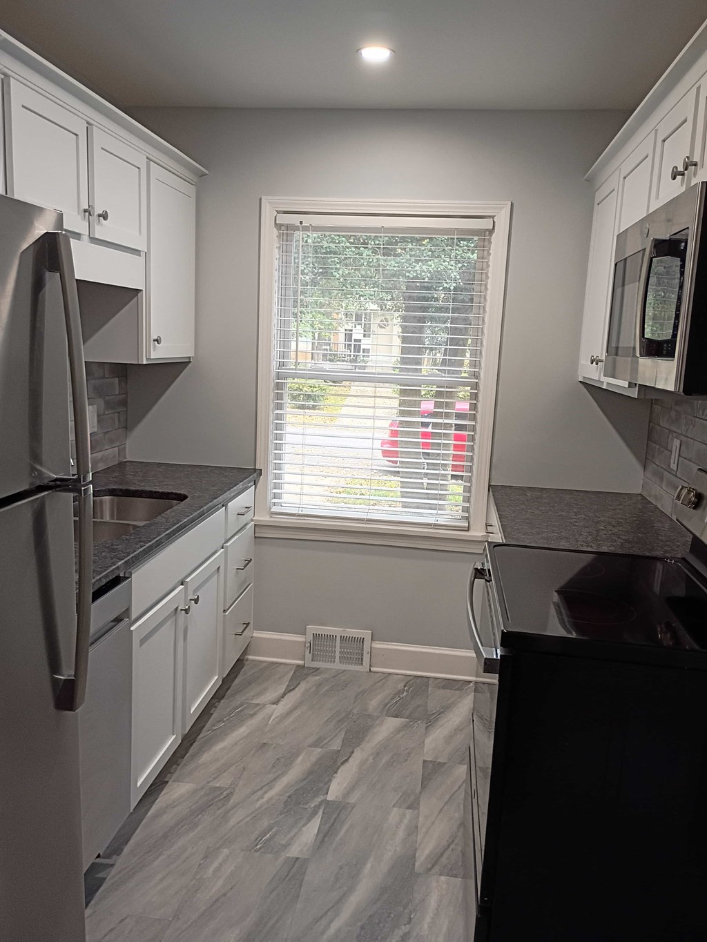 A kitchen with white cabinets and a black countertop.