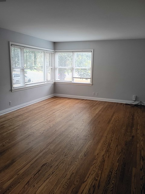 A room with wooden flooring and a window with blinds.