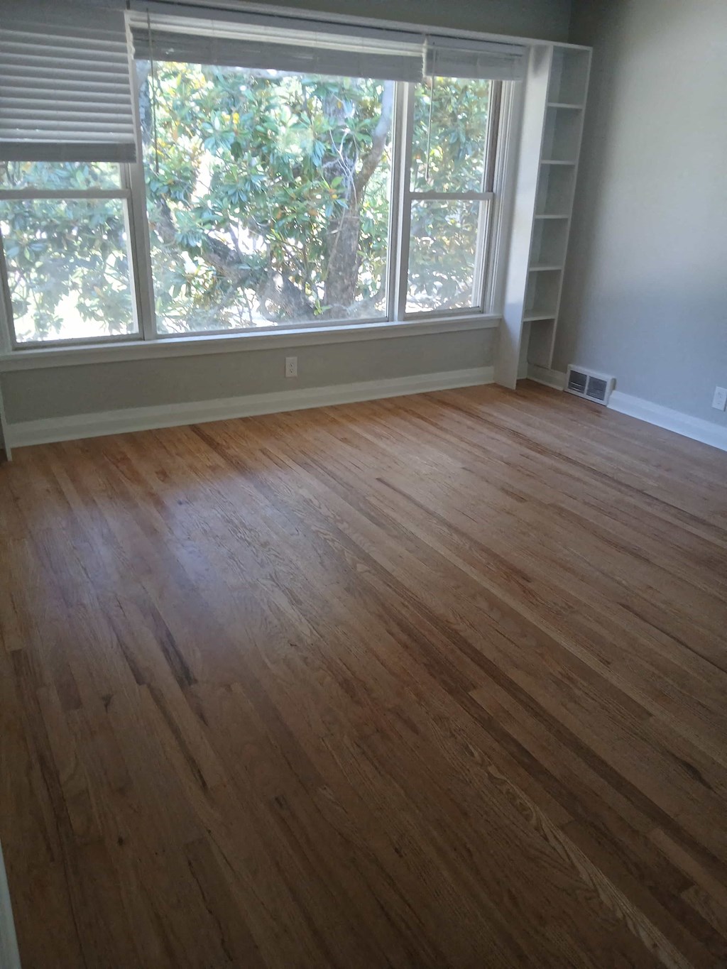 a living room with a wooden floor and a large window