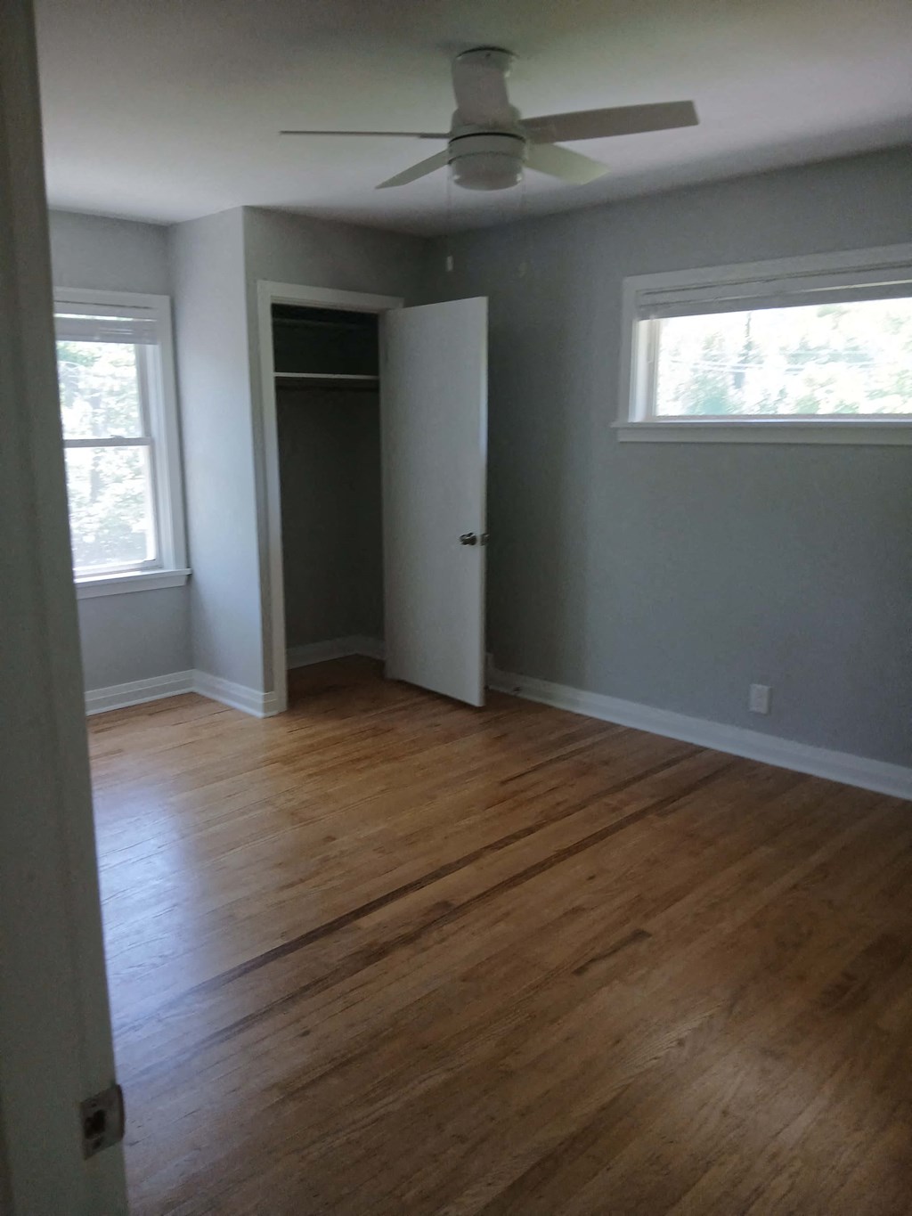 an empty living room with wood floors and a ceiling fan