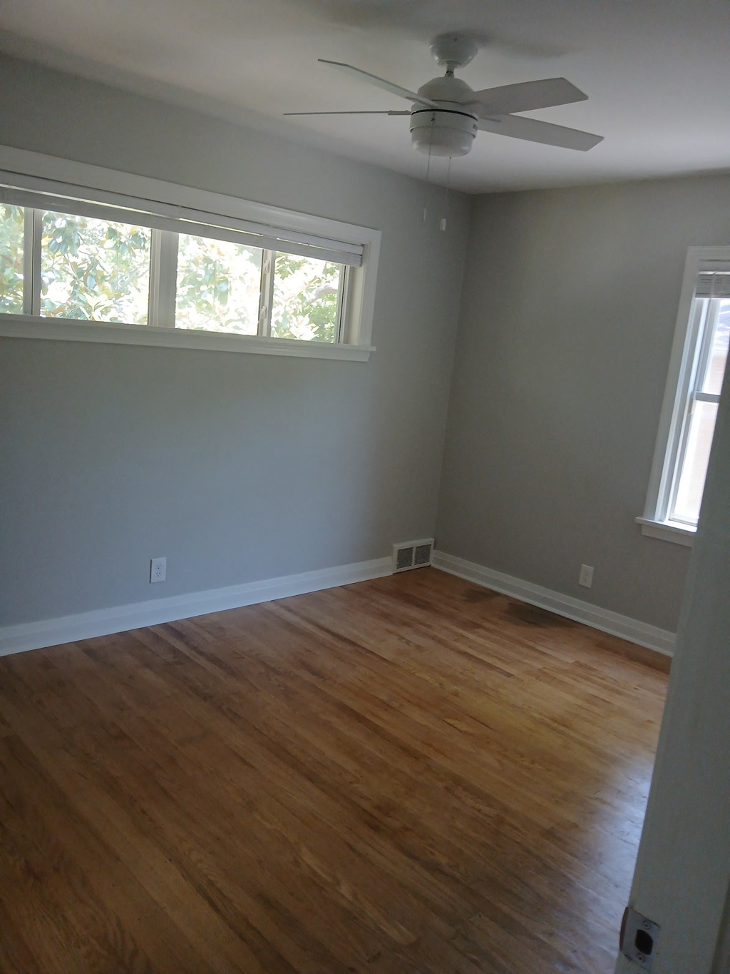 an empty living room with wood floors and a ceiling fan