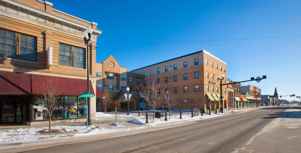 A street view of a town with buildings on both sides and a clear blue sky.