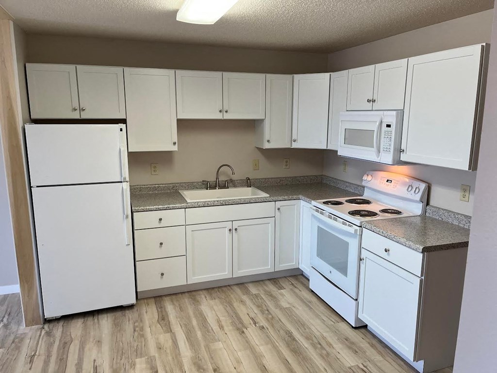 A kitchen with white appliances and cabinets.