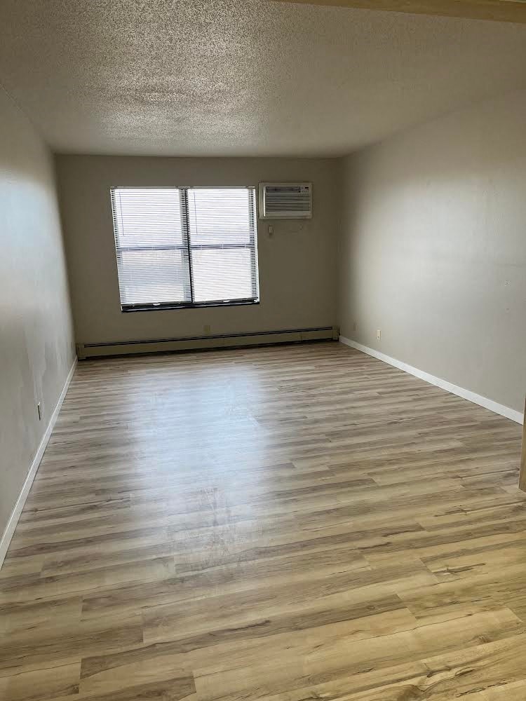 A room with wooden flooring and a window with blinds.