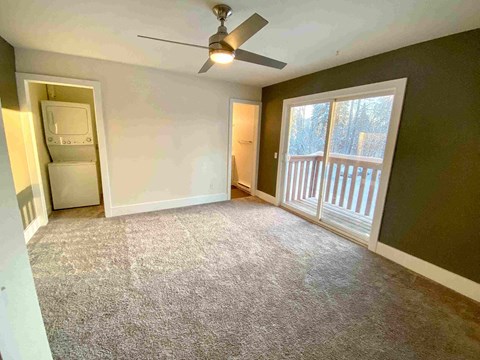 an empty living room with a ceiling fan and a window