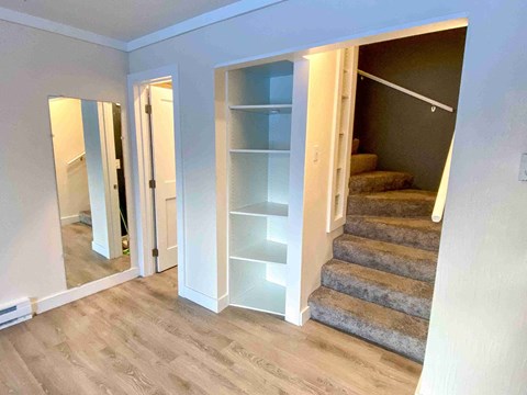 a walk in closet with shelves and stairs in a renovated room