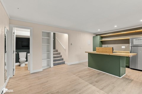 A kitchen area with a green countertop and a staircase in the background.