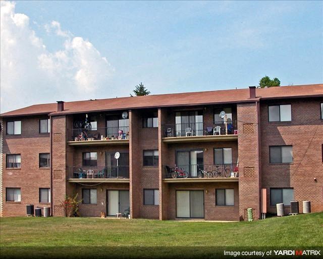 a brick apartment building with balconies and a lawn