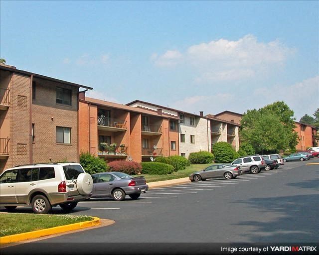 a parking lot with cars in front of an apartment building