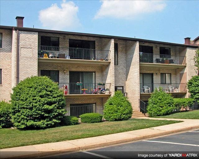 a brick apartment building with balconies and bushes