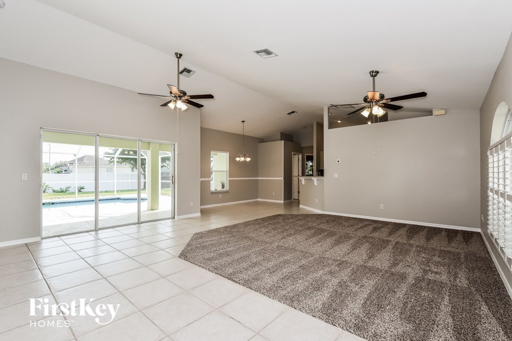 an empty living room with two ceiling fans and a rug