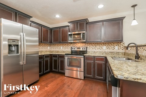 A kitchen with a stainless steel refrigerator and wooden cabinets.