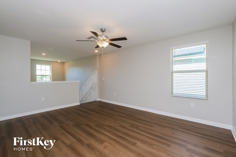 a living room with white walls and a ceiling fan