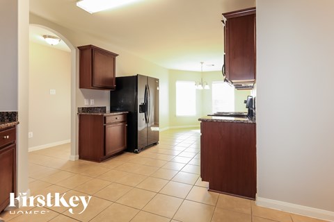 A kitchen with a black fridge and brown cabinets.