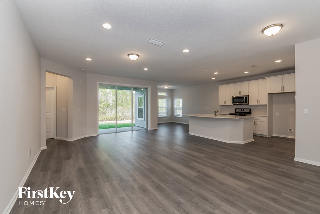 A spacious living room with a kitchen in the background.
