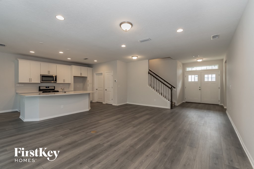A spacious living room with a kitchen area in the background.