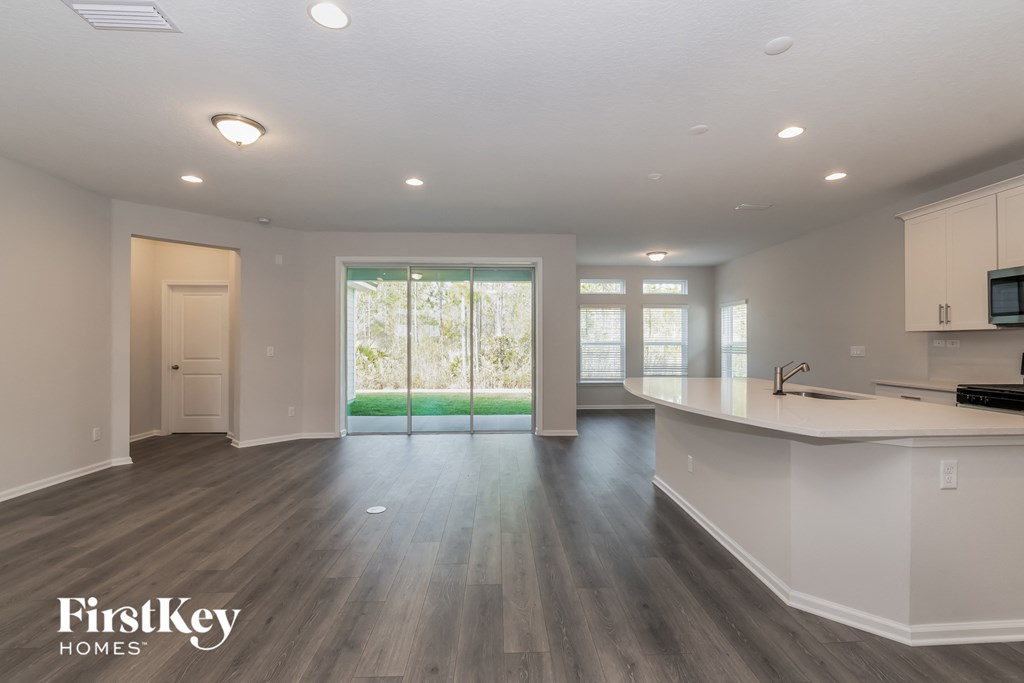 A spacious kitchen and living room with a sliding glass door leading to a backyard.
