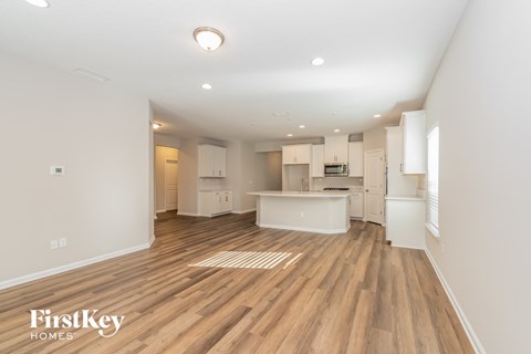 a living room and kitchen with wood flooring and white walls