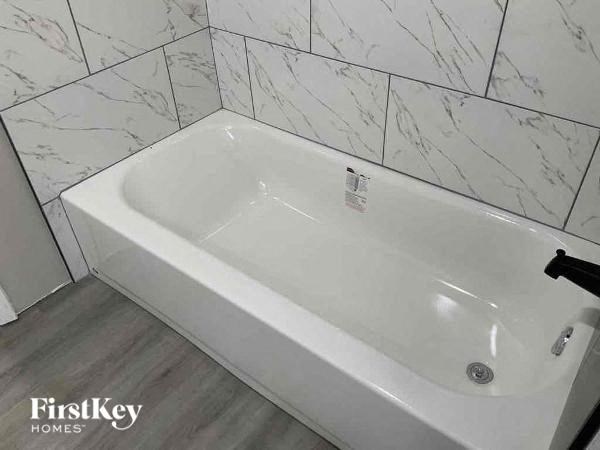 a white bath tub in a bathroom with white tiles