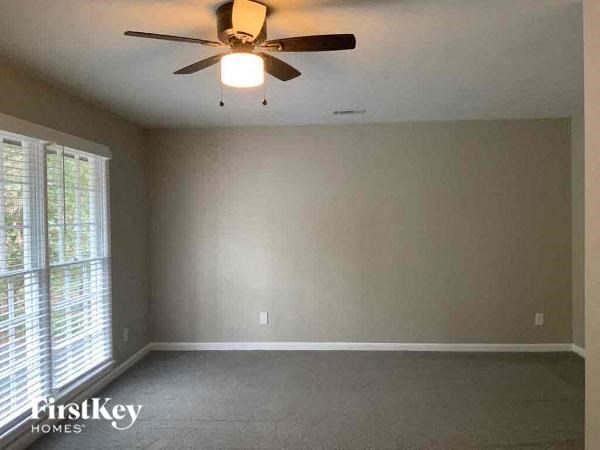 an empty living room with a ceiling fan and a window