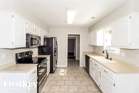A kitchen with white cabinets and black appliances.
