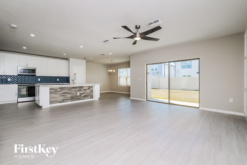 A spacious living room with a ceiling fan and sliding glass doors.