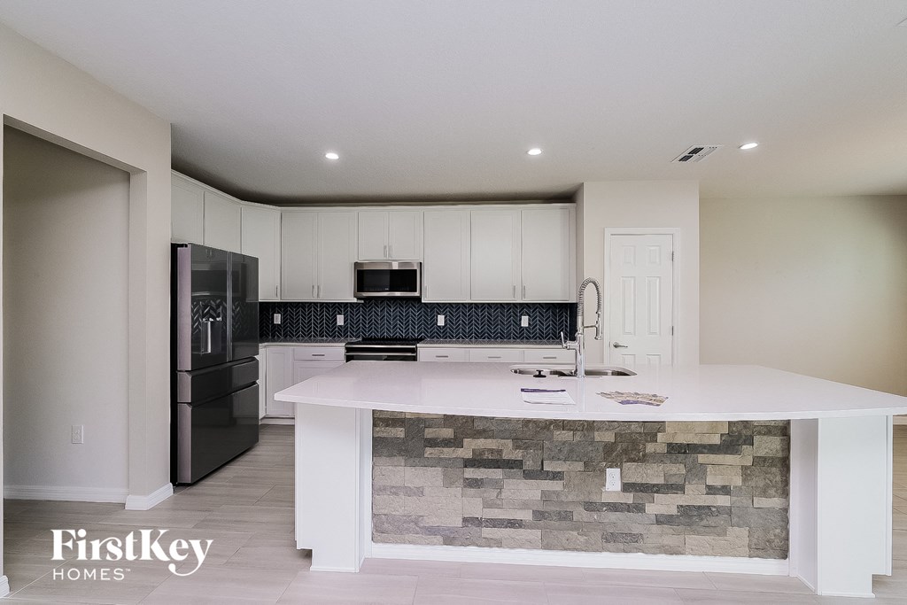 A kitchen with a stone backsplash and a refrigerator.