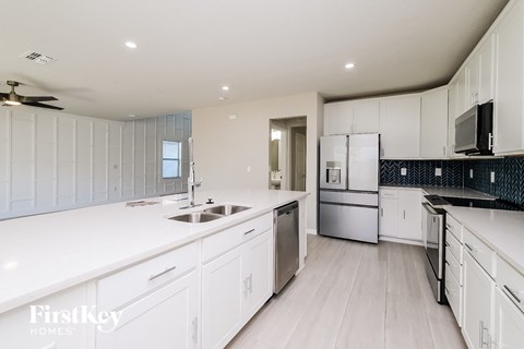 A modern kitchen with white cabinets and a stainless steel refrigerator.