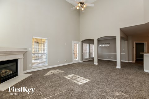 A spacious living room with a fireplace and a carpet on the floor.