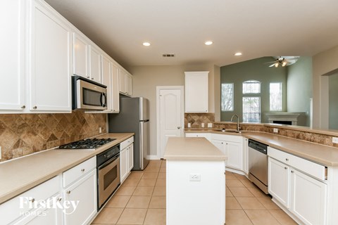 A kitchen with white cabinets and a tiled floor.
