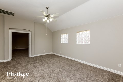A spacious room with a ceiling fan and carpeted floor.