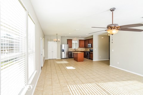 A spacious kitchen and living room with a ceiling fan and tiled flooring.