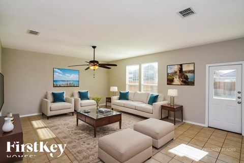 A living room with a couch, chairs, and a ceiling fan.