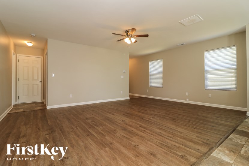 A spacious room with wooden flooring and a ceiling fan.
