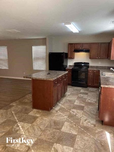 A kitchen with a black oven and brown cabinets.