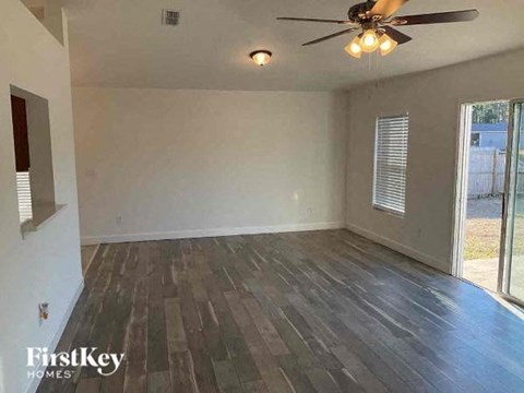 an empty living room with wood floors and a ceiling fan