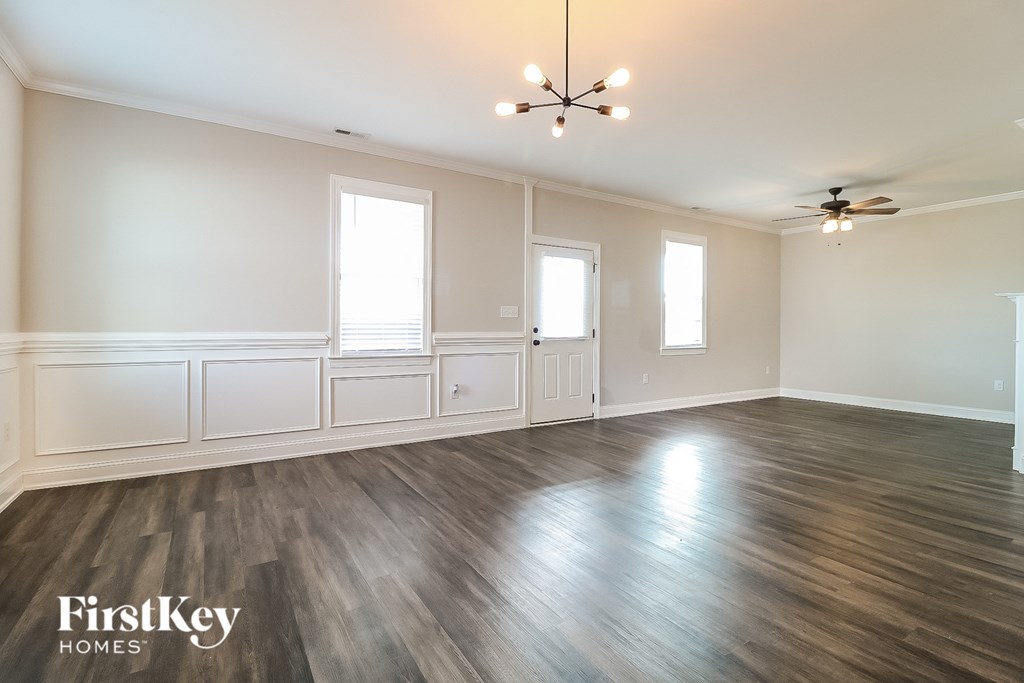 A spacious room with wooden floors and a ceiling fan.