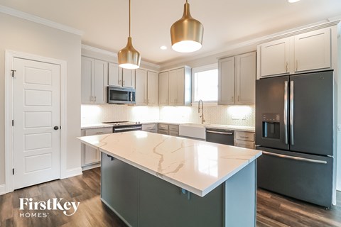 A kitchen with a white island and a black refrigerator.