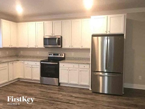 a kitchen with white cabinets and a stainless steel refrigerator