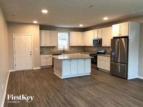 A kitchen with a refrigerator, sink, and cabinets.