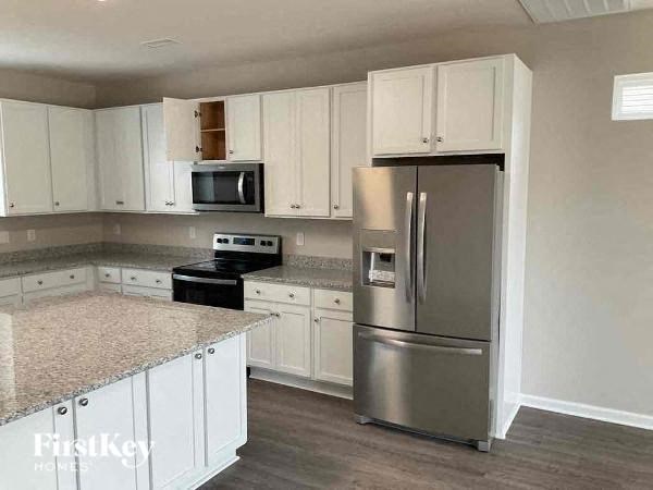 A kitchen with a refrigerator, microwave, and oven.